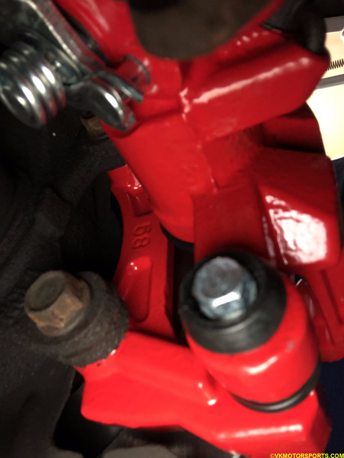 Locate rear bolt behind the caliper